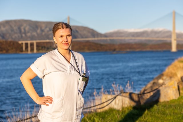 Kvinnelig sykepleier med Helgelandsbrua i bakgrunn