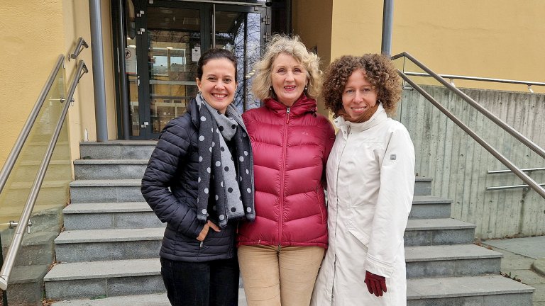 Tre damer står oppstilt utenfor en trapp