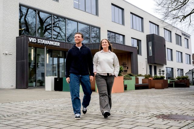 To studenter kommer gående utenfor bygget til VID Stavanger.