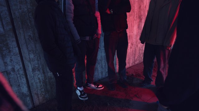 ungdommer som står i mørket i byen. man ser bare beina på dem.