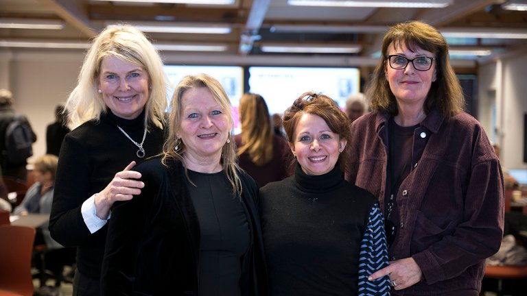 bilde av de fire stående på rekke i klasserom