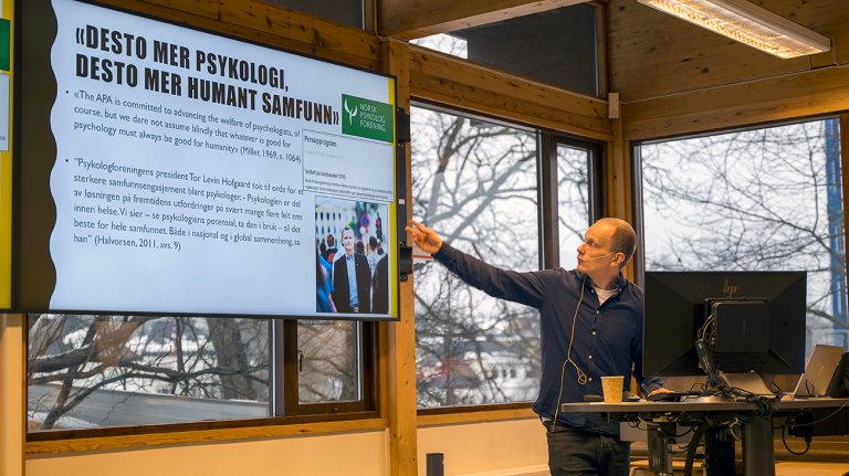 Ole Jacob Madsen sitter foran i klasserom og peker på sin powerpoint-presentasjon.