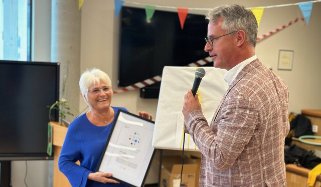 Tove Giske står med et diplom i hendende. Bård Mælan overrekker henne et trykk.