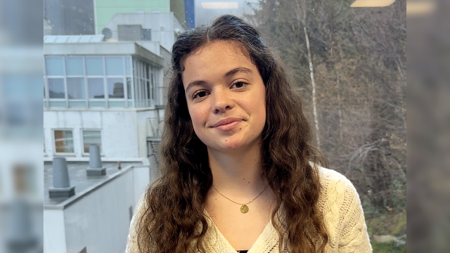 Portrett av Ashlyn tatt inne på VID Bergen, med utsikten fra vinduet som bakgrunn.