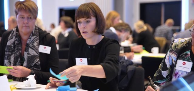 To damer sitter ved et bord og skriver på post-it lapper