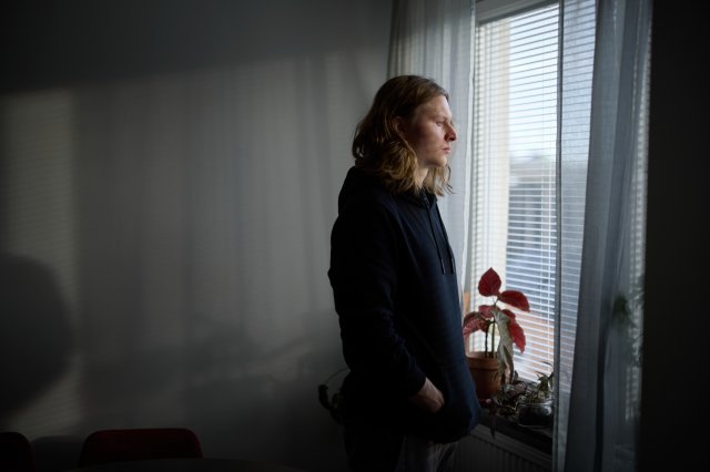 Ung mann står og ser ut av vinduet