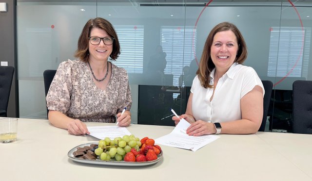 Ingrid og Mona-iren sitter ved et bord i et møterom med ferdig signerte papirer foran seg.