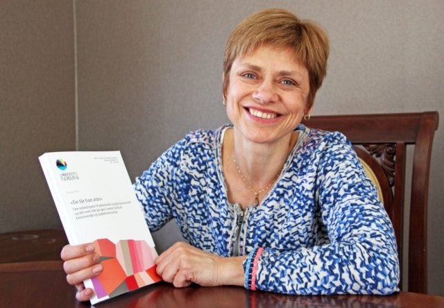 Smilende dame med kort hår som holder et hefte