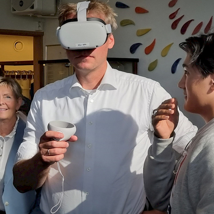 Student Milad Hashemi demonstrerer VR-teknologi som simuleringsverktøy for statsråd Ola Borten Moe. I bakgrunn Ordfører Herøy kommune Elbjørg Larsen. Foto: Helgelandssykehuset HF.