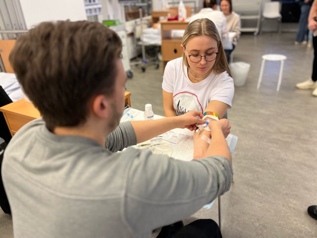 En sykepleier setter en venekanyl på en student i en øvingssituasjon