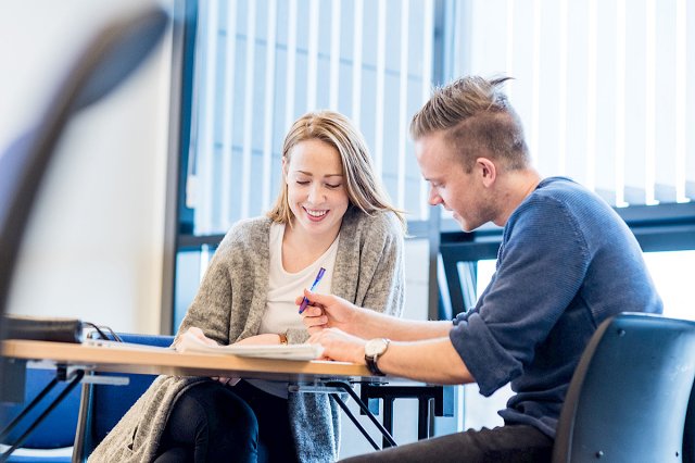En mannlig og kvinnelig student sitter ved et bord og studerer