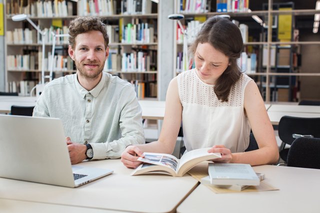 To studenter på et bibliotek sitter og leser