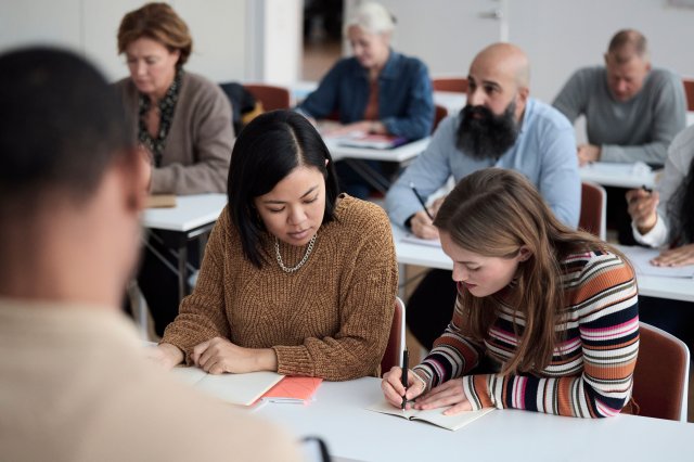 Flere studenter i et klasserom sitter konsentrert i studier