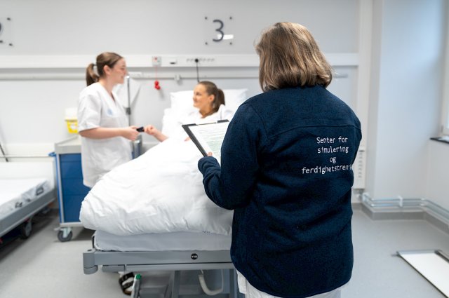 Underviser følger med på studenter som øver seg på Senter for simulering og ferdighetstrening