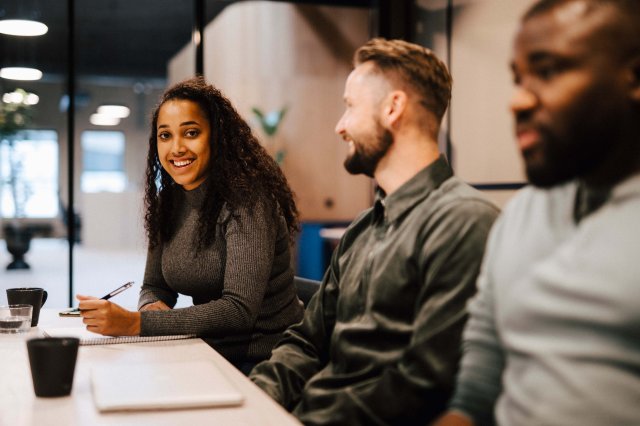 Tre studenter sitter ved en pult