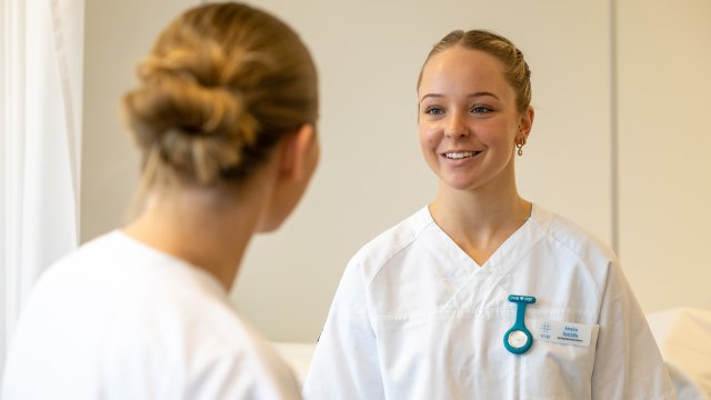 To studenter i sykepleieruniform ser på hverandre