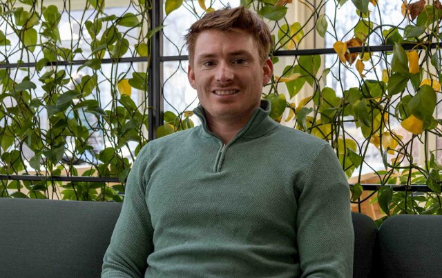 Ung mann sitter foran en begg med planter