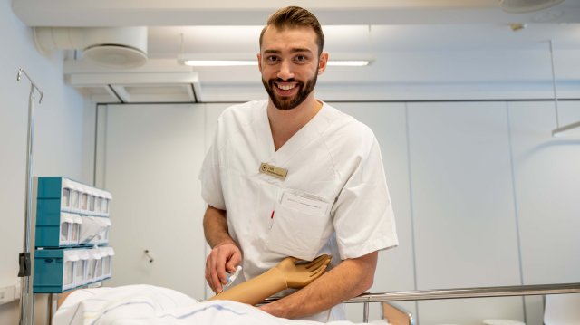 Sykepleier Tim i uniform på jobb ved et sykehus.