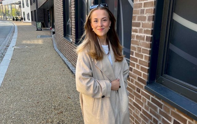 En student står utenfor et mursteinsbygg